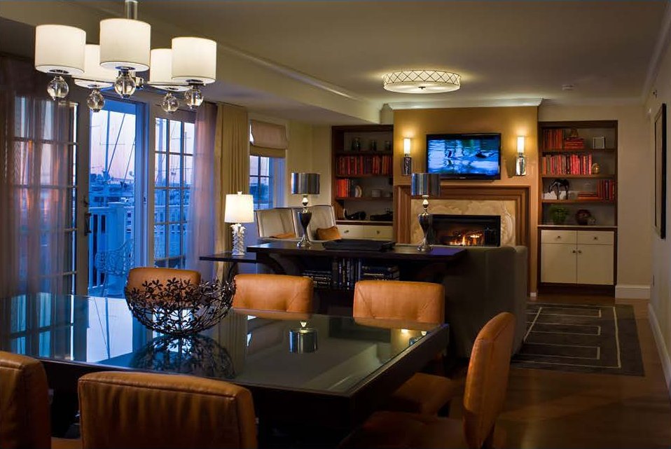 Hotel suite with a display integrated above the fireplace, flanking built-in bookcases and decorative lighting